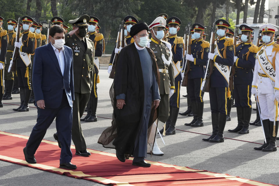Iranian President Ebrahim Raisi, center, reviews an honor guard while departing Tehran's Mehrabad airport for a trip to Oman, Monday, May, 23, 2022. (AP Photo/Vahid Salemi)