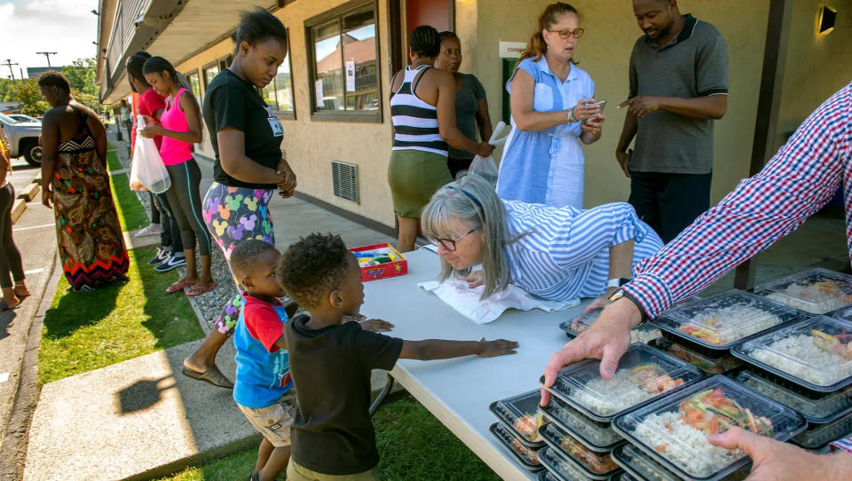 Ellen Koswick, center, of Framingham, serves lunch to Haitian asylum seekers at the Red Roof Inn last summer.