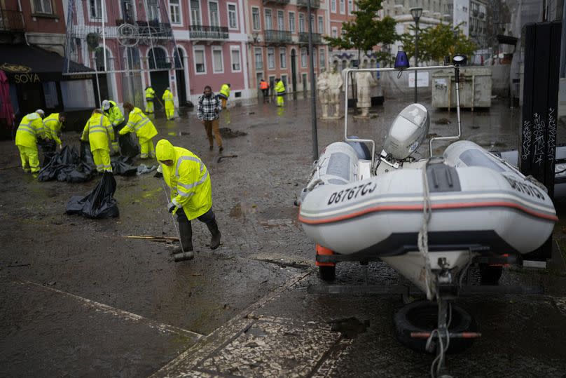 Trabajadores municipales limpian una calle inundada durante la noche en Alges, en las afueras de Lisboa, diciembre de 2022