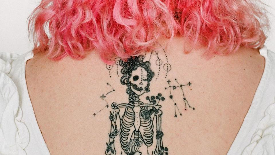 pink-haired woman with skeleton back tattoo