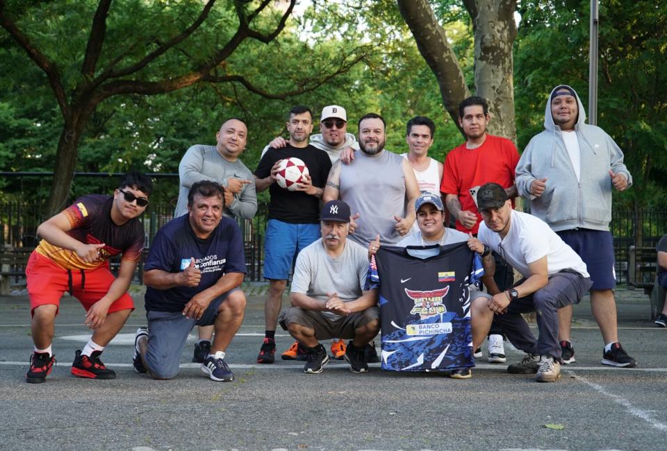 Ecuavoley players and organizers pose for a picture in front of greenery.