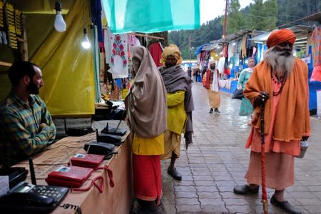 A Hindu pilgrim makes a call at a stall run by a Kashmiri Muslim before their journey towards the holy cave of Amarnath, at a base camp near Pahalgam