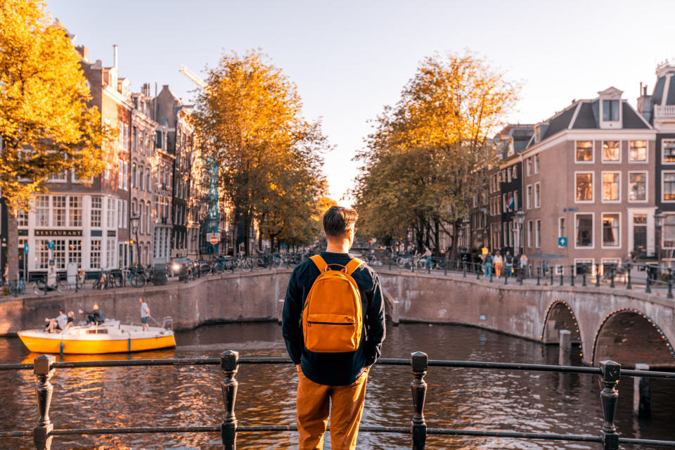 Rear view of a man looking at Amsterdam canal on a sunny day.