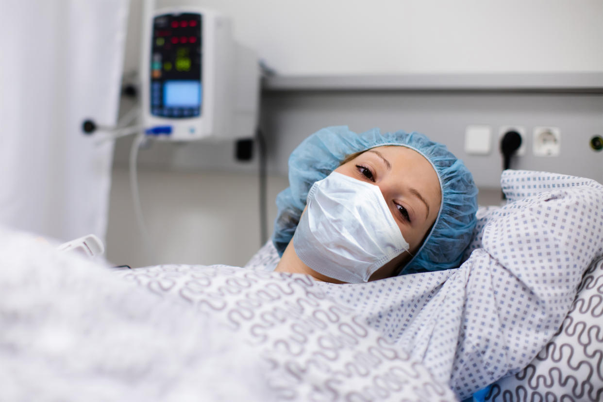 Patient in hospital. Virus outbreak. Young woman wearing face mask in clinic ward recovering from coronavirus disease. Sick person after surgery. Corona virus or flu quarantine.