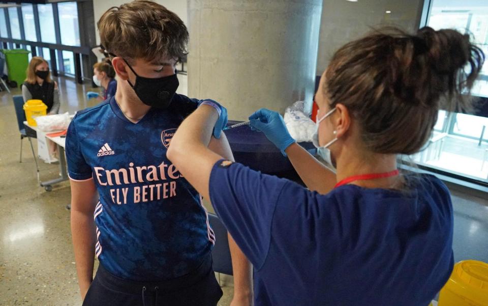 18-year-old Solomon Bird receives a dose of the Pfizer vaccine at a vaccination centre set up at Tottenham Hotspur's football stadium in London - WILL EDWARDS/AFP