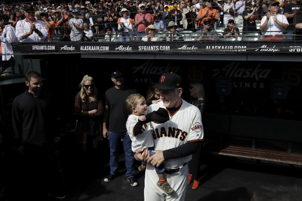 San Francisco Giants manager Bruce Bochy, right, smiles while holding his grandson in the dugout before a baseball game between the Giants and the Los Angeles Dodgers in San Francisco, Sunday, Sept. 29, 2019. (AP Photo/Jeff Chiu)