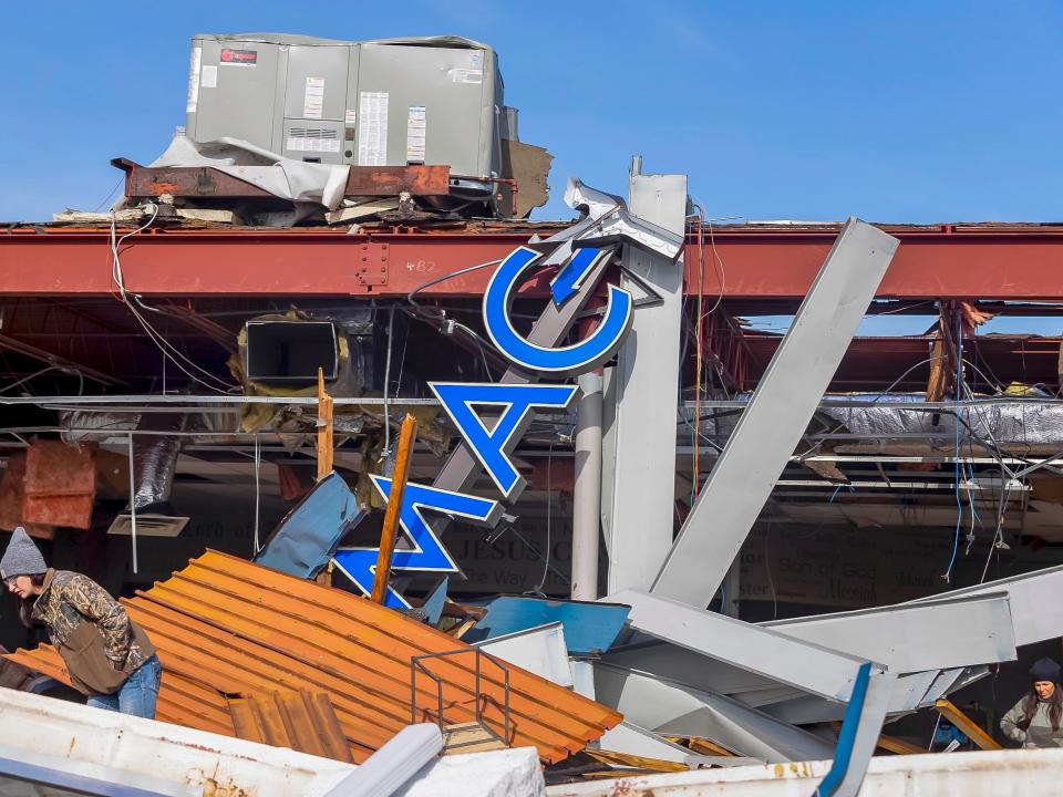 A resident observes damage to a business after a deadly tornado struck in Mayfield, Kentucky, USA, 11 December 2021 (EPA)