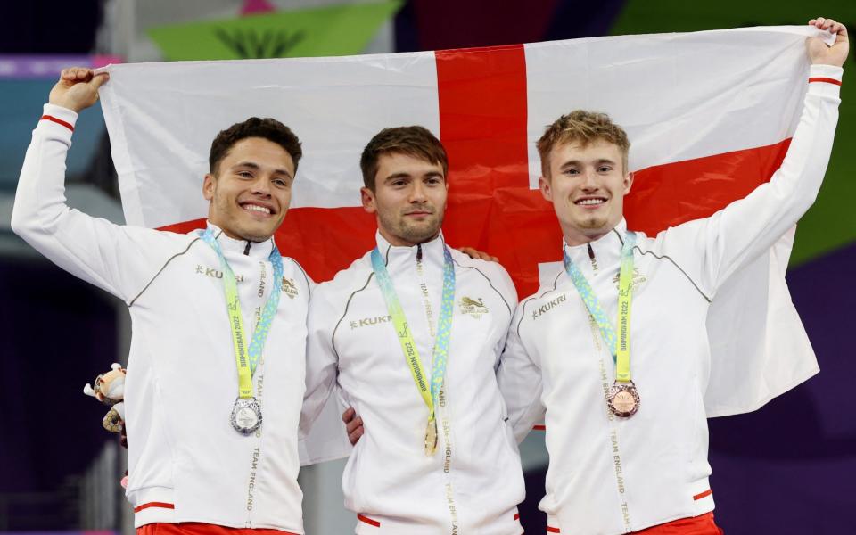 Gold medallist England's Daniel Goodfellow celebrates on the podium alongside silver medallist Jordan Houlden and bronze medallist Jack David Laugher. - REUTERS