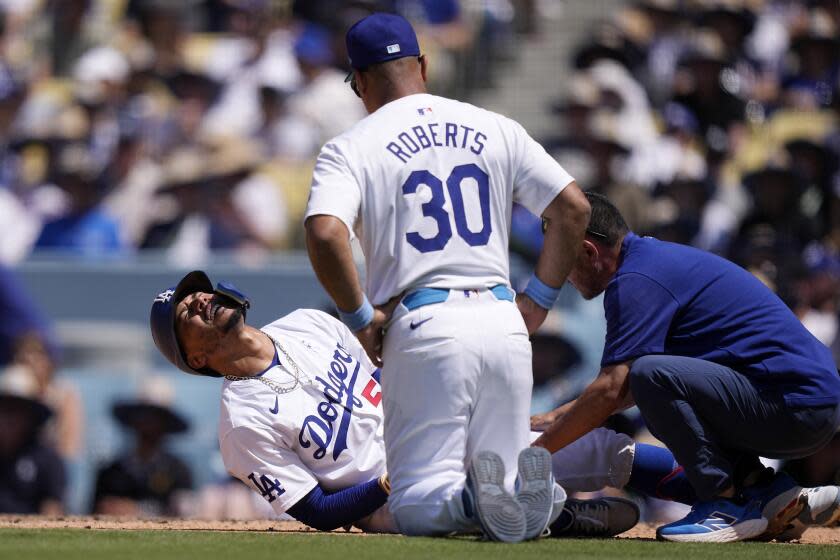 Mookie Betts of the Los Angeles Dodgers (left) writhes in pain on.