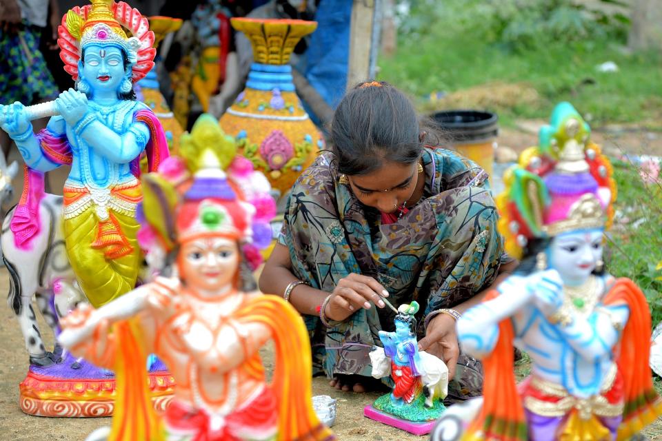 <p>A hawker gives the finishing touches to a Plaster Of Paris (POP) idol of Hindu deity Krishna at a road side stall in Bangalore on August 31, 2018. – ‘Krishna Janmashtami’ is an annual festival that celebrates the birth of Hindu deity Krishna. (Photo by MANJUNATH KIRAN/AFP/Getty Images) </p>