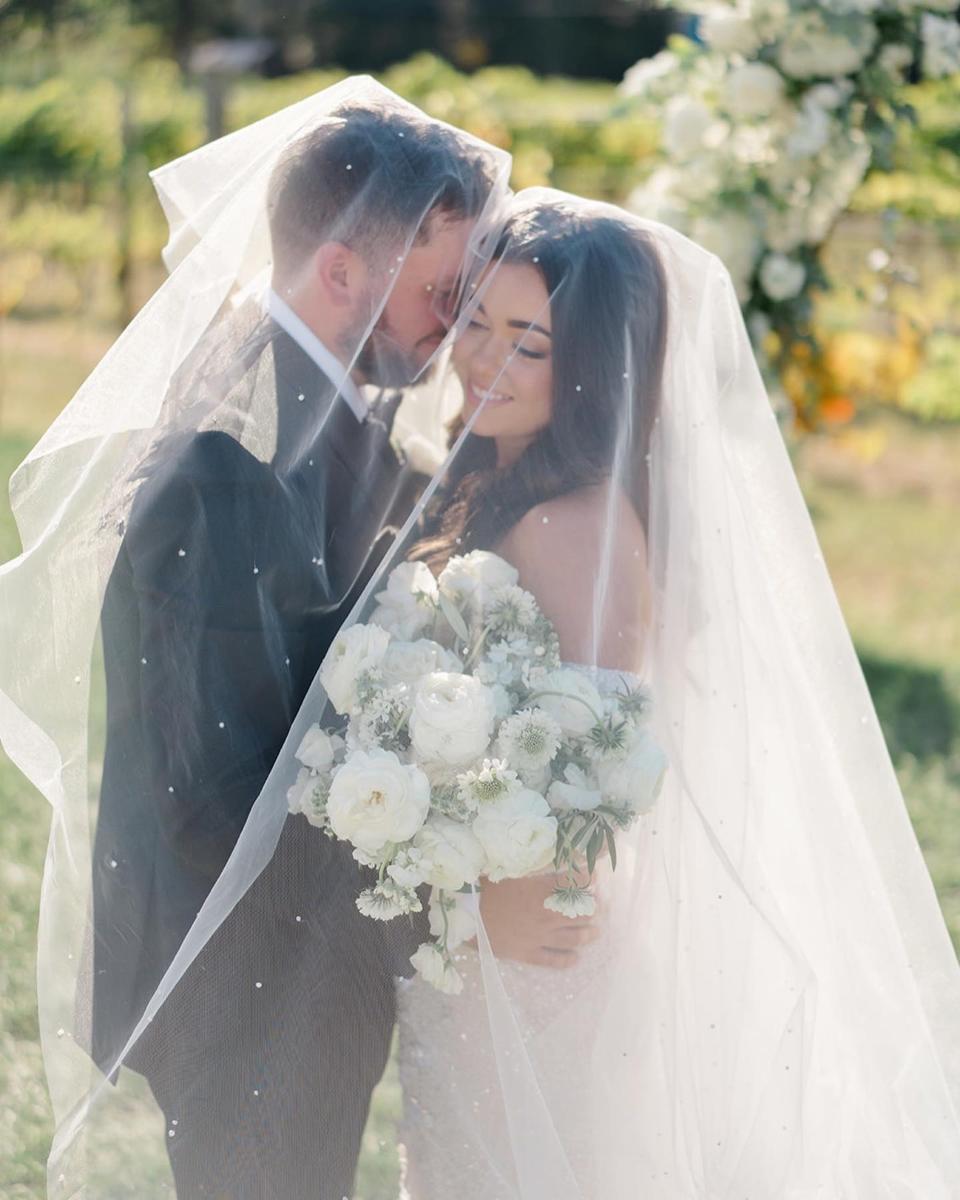 A bride and groom embrace under her veil.