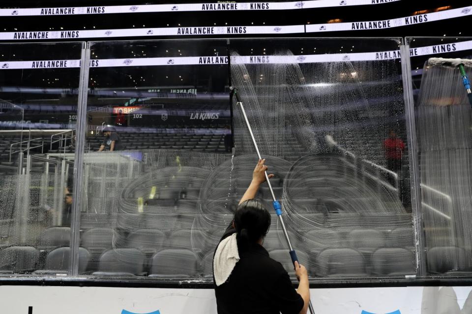 An employee at Crypto.com Arena washes plexiglas panels