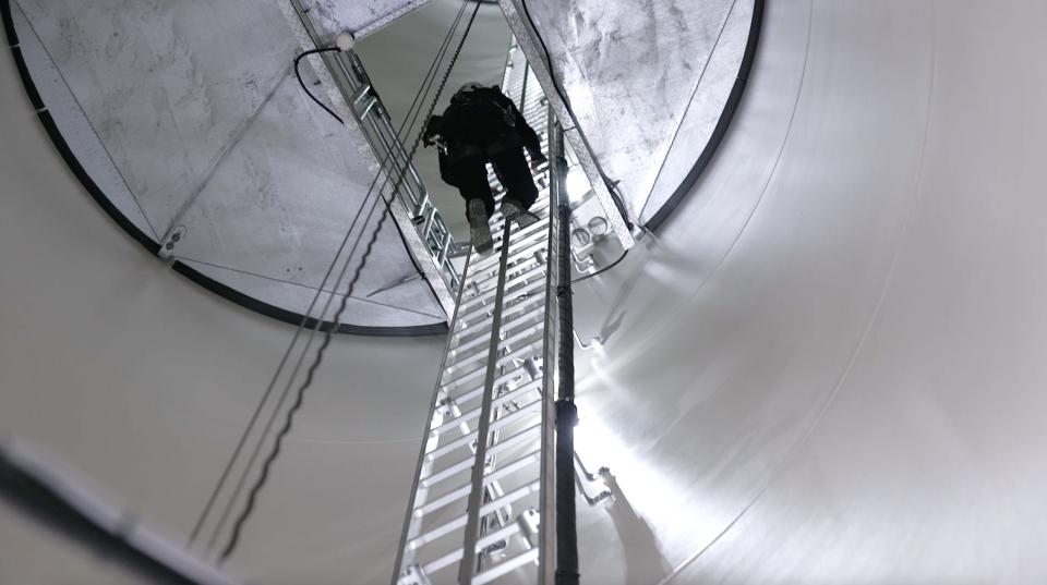 Sardo climbing up a ladder in the interior of a wind turbine.