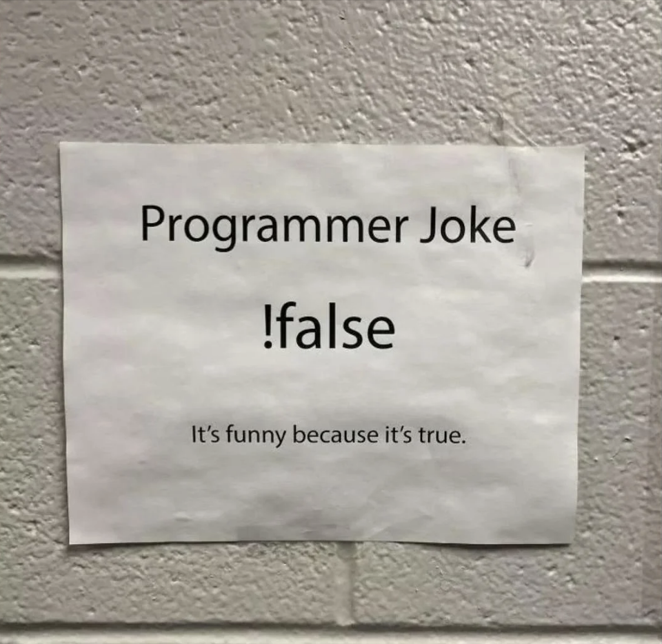 Sign on a wall with a programmer joke that reads '!:false It's funny because it’s true.'