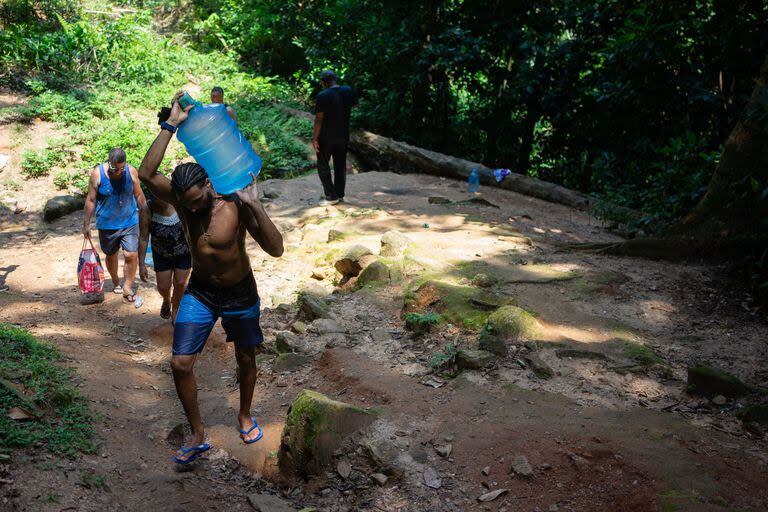 La gente recolecta agua en Rocinha a partir de las vertientes naturales (Photo by Tercio TEIXEIRA / AFP)