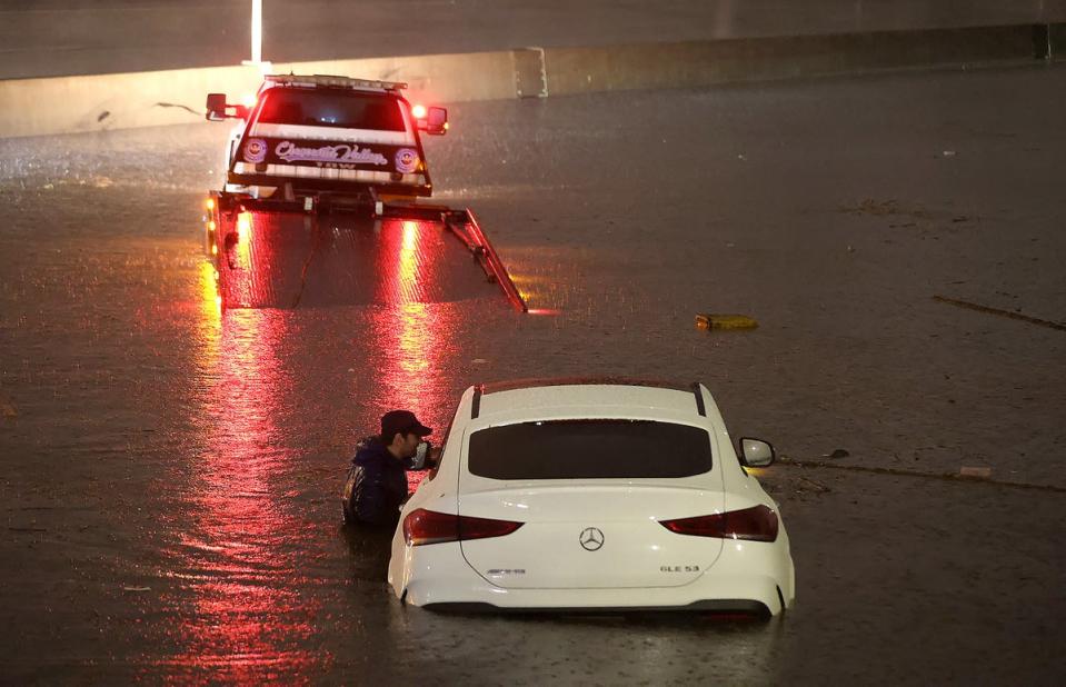 A tow truck driver attempts to pull a stranded car out of floodwaters on the Golden State Freeway (Getty Images)