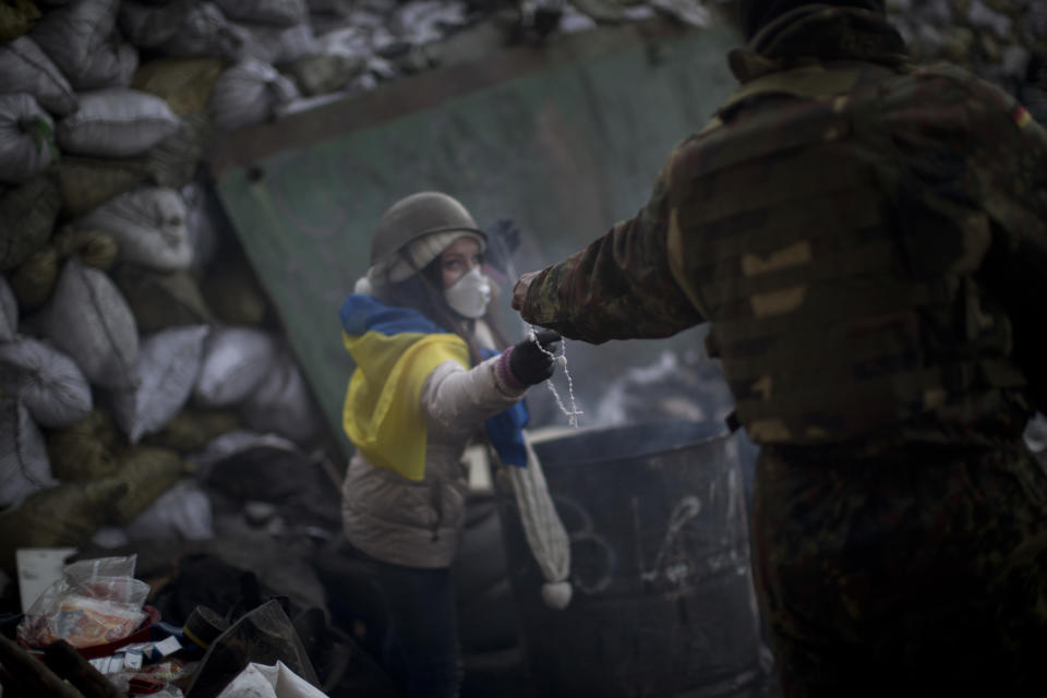 A woman receives a rosary beads from a comrade in a barricade near Kiev's Independence Square, the epicenter of the country's current unrest, Ukraine, Friday, Jan. 31, 2014. Police on Friday opened an investigation into the kidnapping of an opposition activist, who said he was held captive for more than a week and tortured in the latest in a string of mysterious attacks on anti-government protesters in the two-month-long political crisis. (AP Photo/Emilio Morenatti)