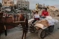 <p>Un niño muestra su agradecimiento junto a su padre sobre unos sacos de harina que dicen "no están a la venta". El personal de la Agencia de la ONU para los Refugiados Palestinos (UNRWA) suministrado harina en los últimos seis meses a más de 380.000 familias que dependen de ese alimento básico para prevenir la hambruna. (Photo by Jehad Alshrafi/Anadolu via Getty Images)</p> 