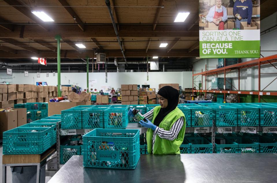 A worker checks expiry dates on bottled and canned products at the Edmonton Food Bank on July 21, 2023. Some people are wondering why the money from Canada Bread’s fine isn’t being used to support food banks or other anti-poverty measures. THE CANADIAN PRESS/Jason Franson.