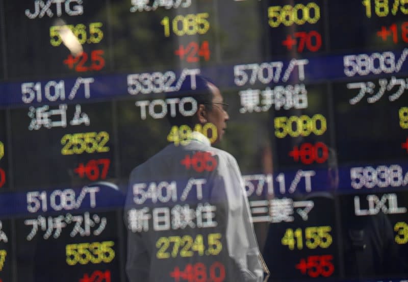 Passersby are reflected in an electronic stock quotation board outside a brokerage in Tokyo, Japan, October 23, 2017. REUTERS/Issei Kato