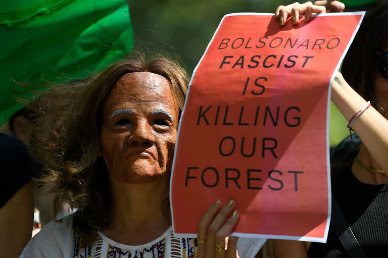 Una activista climática enmascarada sostiene un cartel contra el presidente brasileño Jair Bolsonaro durante una manifestación en Barcelona contra los incendios en el Amazonas el 23 de agosto de 2019
