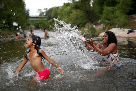 Eight months pregnant Honduran migrant Erly Marcial, 21, plays with her daughter Maria, 6, in the river in Tapanatepec, Mexico, November 6, 2018. REUTERS/Carlos Garcia Rawlins