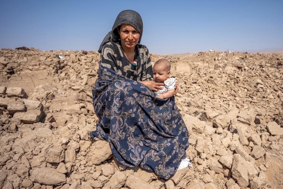 Twenty-five-year-old Hakima sits in her destroyed village with her her 6 month old daughter, Nasifa in Chahak, Injil District, western Afghanistan.