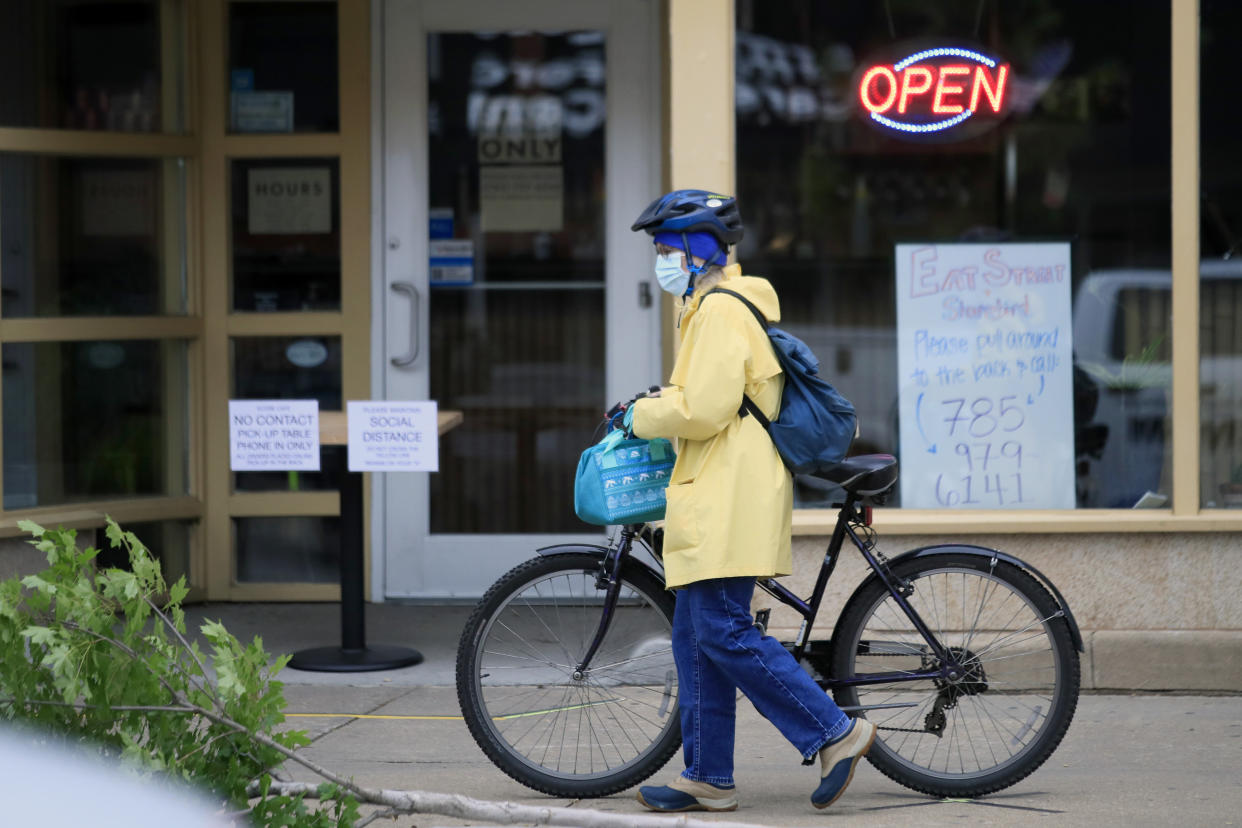 A customer arrives for a pickup dinner at a downtown restaurant In Lawrence, Kan., Monday, May 4, 2020. Restaurant dining rooms, retail stores and some offices began reopening Monday after Kansas lifted a statewide stay-at-home order, though some business owners hesitated, still concerned about the novel coronavirus. (AP Photo/Orlin Wagner)
