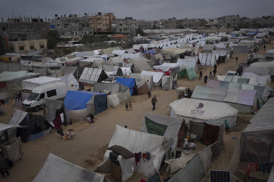 Palestinos desplazados por la ofensiva terrestre israelí en la Franja de Gaza caminan en el campamento improvisado en Rafah, el martes 23 de enero de 2024. (AP Foto/Fatima Shbair)