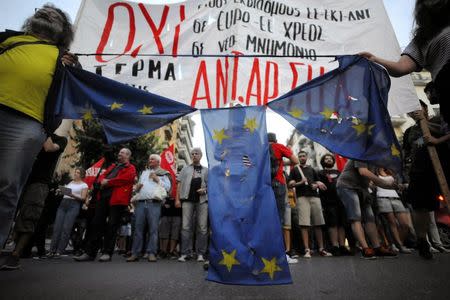 Anti-EU protesters hold a burned and torn European Union flag during a protest at the northern city of Thessaloniki, Greece July 1, 2015. REUTERS/Alexandros Avramidis