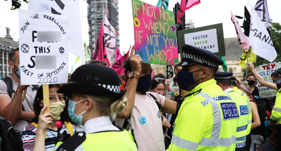 Pictured are Extinction Rebellion activists holding signs in front of a line of police in London.