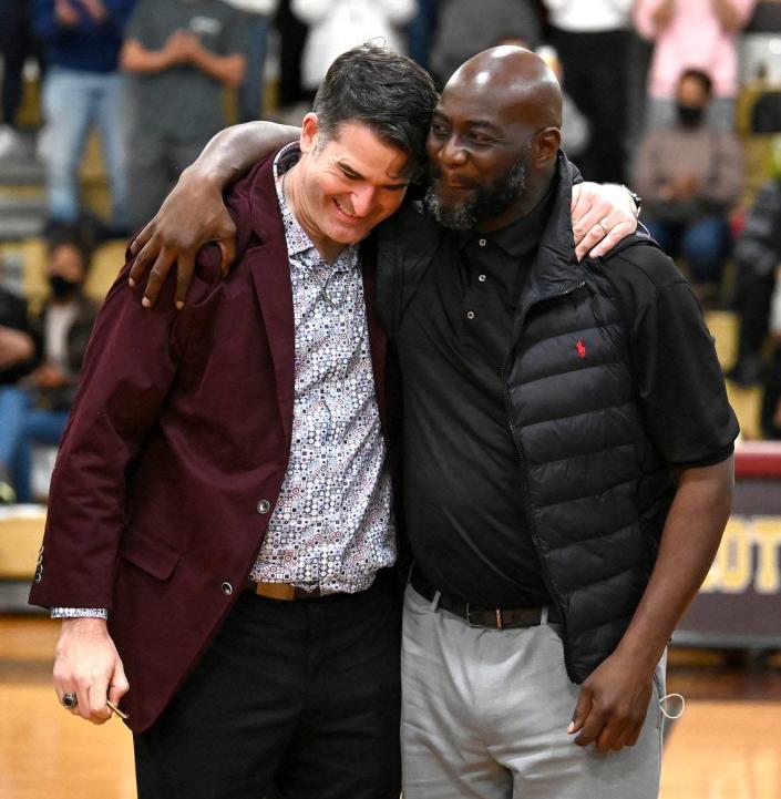 Former West Charlotte Lions Eric Trosch, left and Thadius Bonaparte, right, hug during a ceremony honoring the 1991 and 1992 state championship teams on Friday, January 14, 2022 at West Charlotte High School.