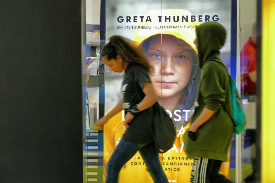 People walking in front of a poster.