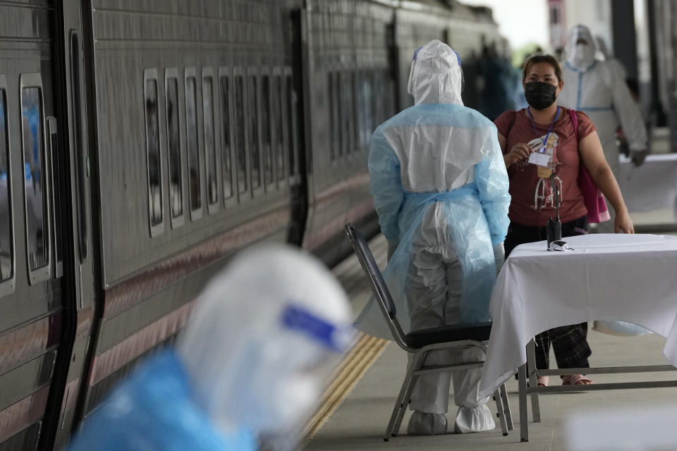 A health worker talks with a woman, who is among a group of people infected with COVID-19, as she arrived at Rangsit train station in Pathum Thani Province, Thailand, Tuesday, July 27, 2021. Thai authorities began transporting some people who have tested positive with the coronavirus from Bangkok to their hometowns on Tuesday for isolation and treatment, to alleviate the burden on the capital’s overwhelmed medical system. (AP Photo/Sakchai Lalit)