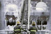 <p>Philadelphia firefighters work the scene of an overnight blaze in west Philadelphia, Feb. 16, 2015, as icicles form where water from their hoses has frozen. (Photo: Jacqueline Larma/AP) </p>