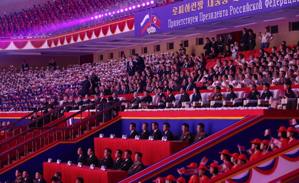 Vladimir Putin and Kim Jong Un sit among a crowd of attendees as they watch a gala concert.