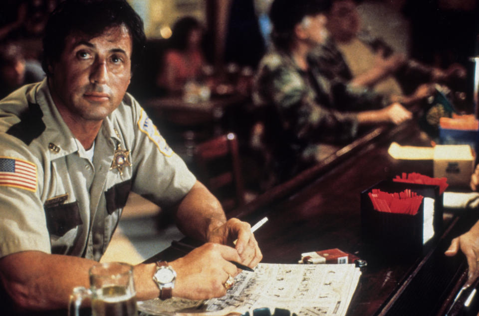 A sad police officer sits alone in a crowded bar