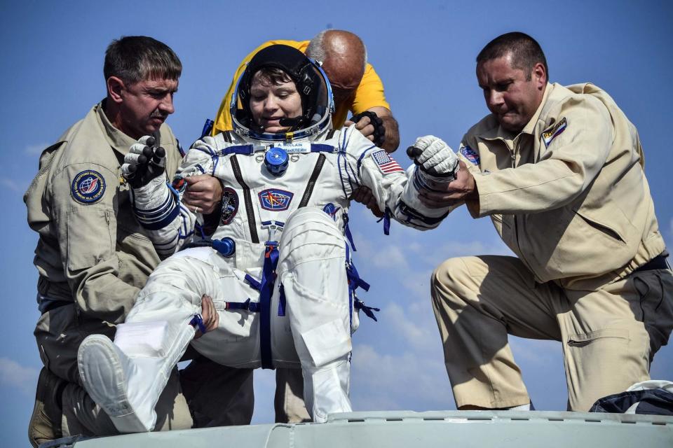 Pictures show NASA astronaut Anne McClain being helped from her capsule after safely returning to Earth following a six-month stint on the International Space Station. The American looked thrilled to have completed her maiden flight. The Soyuz capsule, inset, carrying Ms McClain and two other astronauts, Russian Oleg Kononenko and Canadian David Saint-Jacques, landed on the steppes of Kazakhstan at 8.47am local time today after a three-and-a-half-hour flight from the orbiting lab.They were put on camping chairs in the sun for some initial medical checks.When asked by a reporter if he liked the weather, Mr Kononenko said he was “happy to see any kind of weather” after more than 200 days in space.