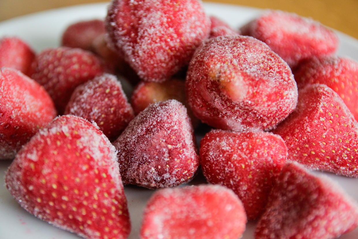 Frozen strawberries on a white plate. Frozen strawberries have been linked to hepatitis A. 