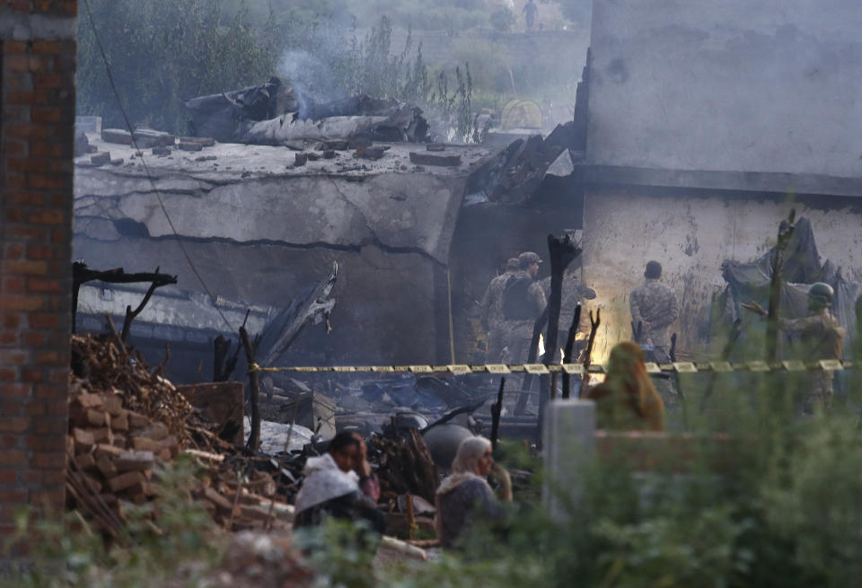 Pakistan army officials examine the site of a plane crash in Rawalpindi, Pakistan, Tuesday, July 30, 2019. A small Pakistani military plane crashed into a residential area near the garrison city of Rawalpindi before dawn, killing some people, officials said. (AP Photo/Anjum Naveed)