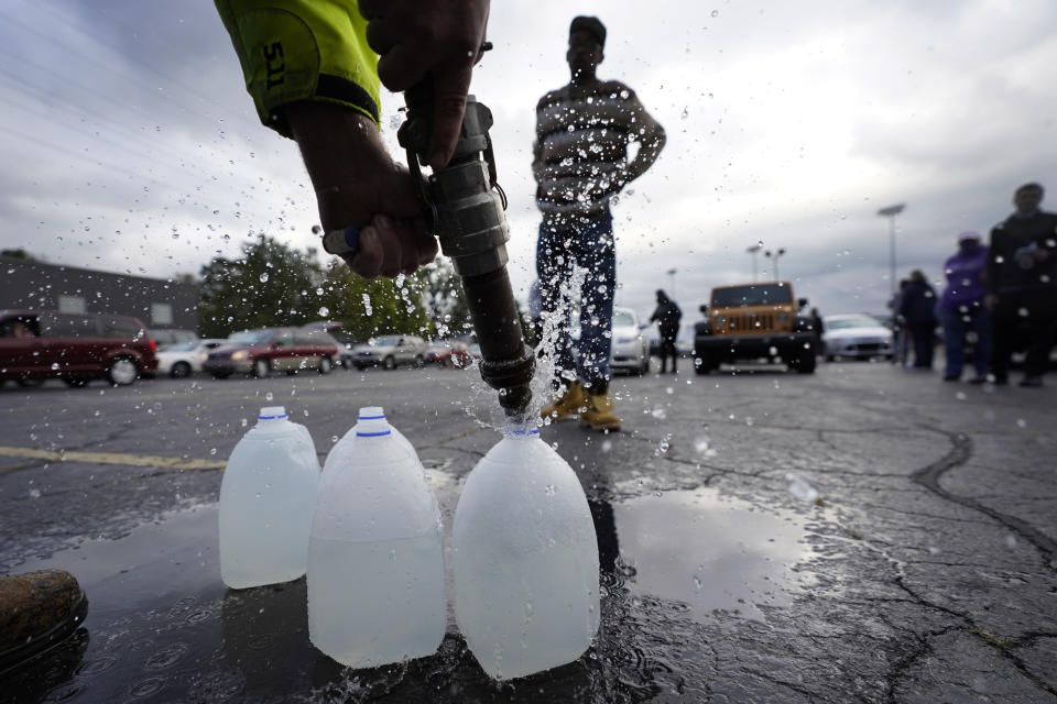 FILE - Kevin Stack with the Berrien County Road Department fills up jugs with non-potable water for Elliot Napier in the Benton Harbor High School parking lot Oct. 21, 2021, in Benton Harbor, Mich. Lead pipes have caused harm for decades. In recent years, residents in Newark, N.J., and Benton Harbor, were forced to use bottled water for basic needs like cooking and drinking, after tests revealed elevated levels of lead. (AP Photo/Charles Rex Arbogast, File)