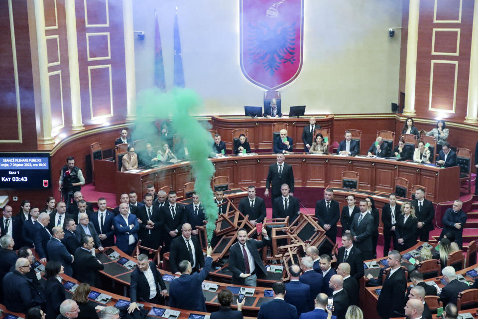Democratic lawmakers throw flares during a parliament session in Tirana, Albania, Thursday Dec. 7, 2023. The Albanian Parliament on Thursday passed the annual budget and other draft laws in a disrupted vote from the opposition using flares and noise to protest against what they consider as an authoritarian rule from the governing Socialist Party. (AP Photo/Armando Babani)