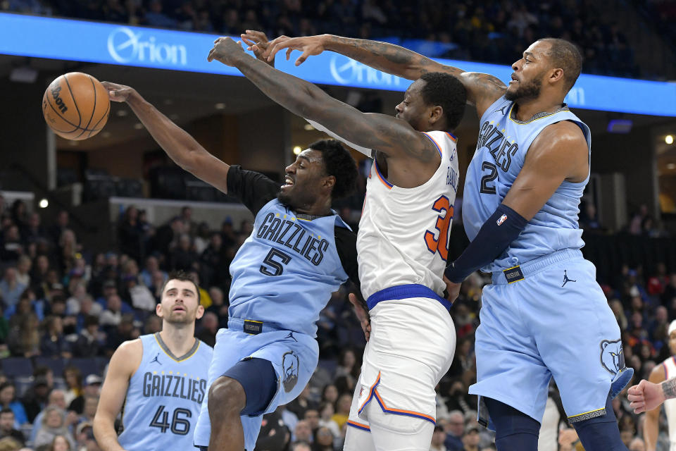 Memphis Grizzlies guard Vince Williams Jr. (5), New York Knicks forward Julius Randle (30) and Grizzlies forward Xavier Tillman (2) reach for the ball during the first half of an NBA basketball game Saturday, Jan. 13, 2024, in Memphis, Tenn. (AP Photo/Brandon Dill)