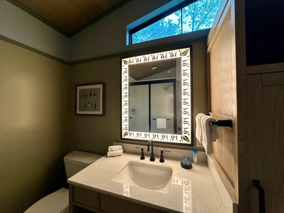 Bathroom sink with mirror with lit-up edges above it