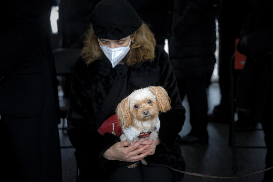 Maria Popa the partner of Iancu Tucarman holds Lady, the family dog, during his funeral, at a Jewish cemetery in Bucharest, Romania, Monday, Jan. 11, 2021. Tucarman, one of the last remaining Holocaust survivors in Romania, on was buried after dying from COVID-19 last week at the age of 98. (AP Photo/Vadim Ghirda)