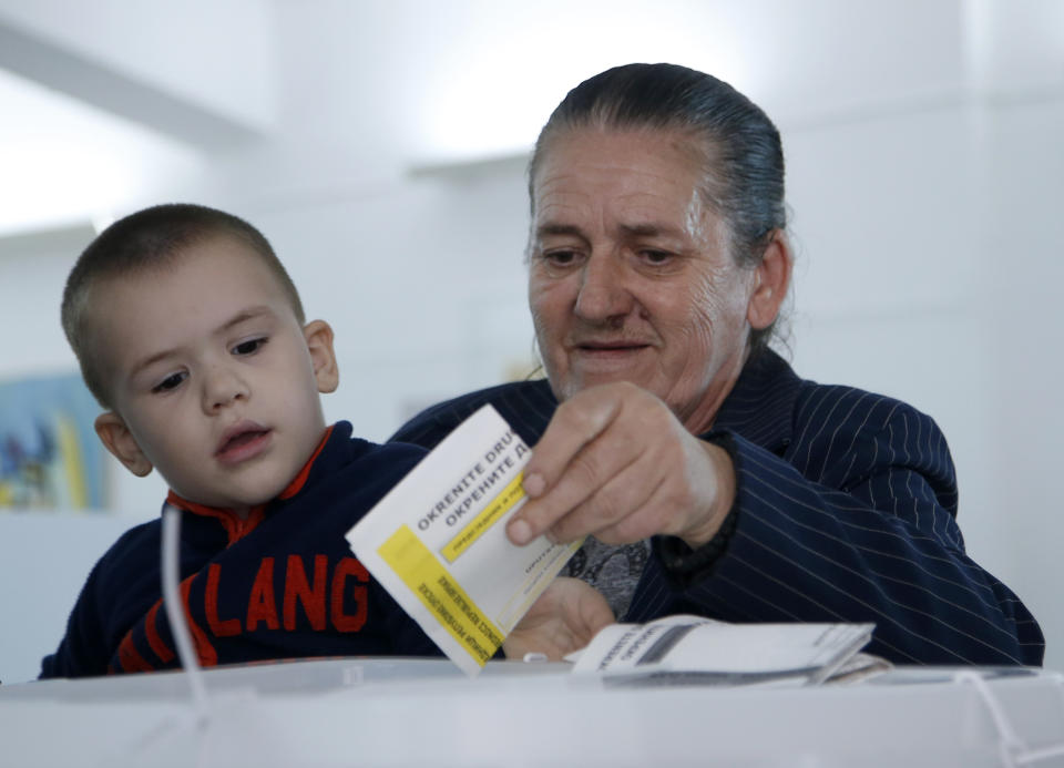 A woman with a child casts her ballot at a polling station in Laktasi, northwest of Sarajevo, Bosnia, Sunday, Oct. 7, 2018. Bosnians were voting Sunday in a general election that could install a pro-Russian nationalist to a top post and cement the ethnic divisions of a country that faced a brutal war 25 years ago. (AP Photo/Darko Vojinovic)