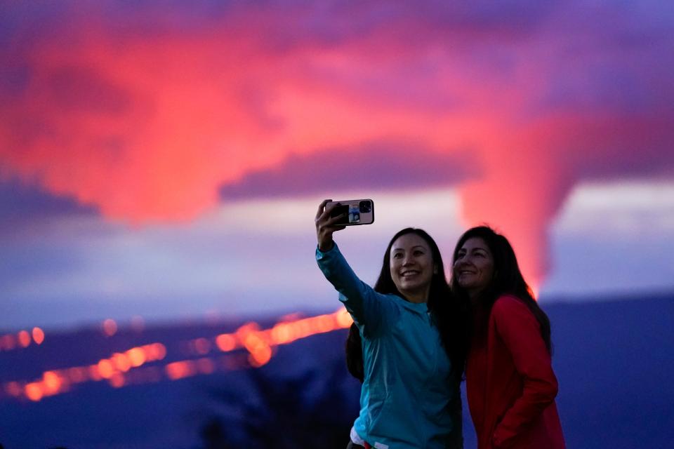 Ingrid Yang, left, and Kelly Bruno, both of San Diego, take a photo in front of lava erupting from Hawaii's Mauna Loa volcano Wednesday, Nov. 30, 2022, near Hilo, Hawaii (AP)