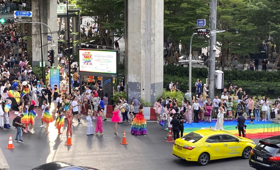 A procession of people dressed in vibrant outfits wait their turn to walk the rainbow carpet at the end of the Pride parade in Bangkok on Sunday, June 4, 2023. LGBTQ+ people from China who are frequently scorned and ostracized at home are coming to Thailand in droves. They're drawn by the freedom to be themselves. Bangkok is only a 5-hour flight from Beijing, and Thailand's tourism authorities actively promote its status as among the most open to LGBTQ+ people in the region.(AP Photo/Donna Edwards)