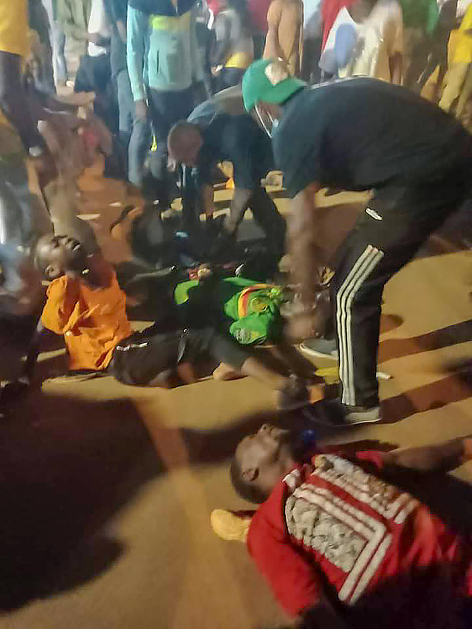 People assist victims of a stampede outside a stadium hosting an African Cup of Nations soccer game in Yaounde, Cameroon, Monday Jan. 24, 2022. Several people have died in a stampede that happened as crowds struggled to get access to Olembe Stadium to watch the host country play Comoros in a last 16 knockout game in Africa's top soccer tournament. (AP Photo/Thierry Noukeu)