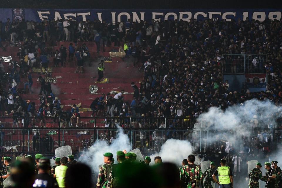 Foto yang diambil pada 1 Oktober 2022 ini memperlihatkan petugas keamanan (bawah) di lapangan Stadion Kanjuruhan Malang, Jawa Timur.  - Sedikitnya 127 orang tewas di sebuah stadion sepak bola di Indonesia pada akhir 1 Oktober, ketika para penggemar menyerbu stadion dan polisi membalas dengan gas air mata, yang memicu penyerbuan, kata para pejabat.  (Foto oleh AFP) (Foto oleh STR/AFP via Getty Images)